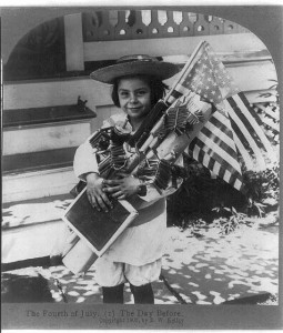 A child with flags and fireworks for the Fourth of July, circa 1906.