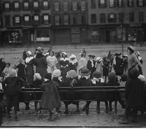 Schoolchildren, two holding flags, dress up for a Thanksgiving pageant in 1911.