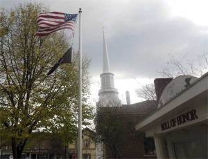 U.S. and MIA flags fly in an autumn village square near a memorial to fallen servicemen. (James Breig photo)