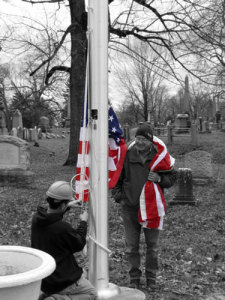 Mike Cronin holds the new American Flag while Sean raises it onto the new flagpole.