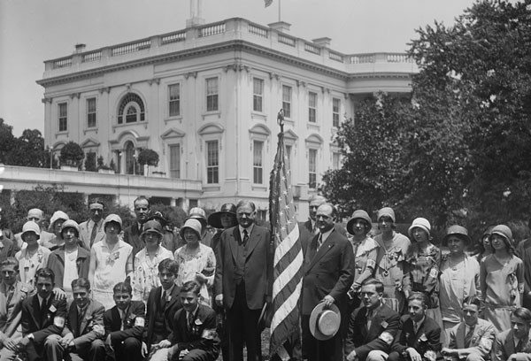 American flag flies on White House in 1929 while President Hoover stands next to one to welcome teens. (Library of Congress)