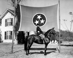 In 1938, a man poses on a horse with the Tennessee state flag as background. (Tennessee State Library and Archives)