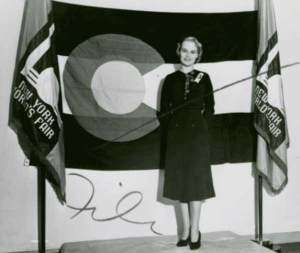 A woman poses before the Colorado flag during the 1939 World's Fair in New York City. (New York Public Library)