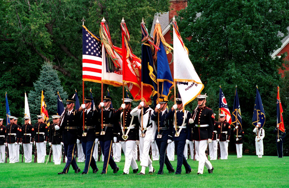 A joint color guard carries the U.S. Flag, Army Service Flag, Marine Corps Flag, Navy Service Flag, Air Force Service Flag, Coast Guard Service Flag.