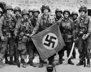 Soldiers display a captured Nazi flag.