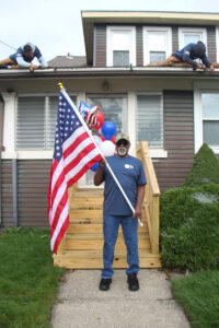 Capital region Army National Guard Master Sergeant Michael Slaughter stand proudly with his new American flag from Gettysburg Flag Works. Meanwhile, the Brothers That Just Do Gutters work on installing his new heated gutter system as part of their Gutters For Good program