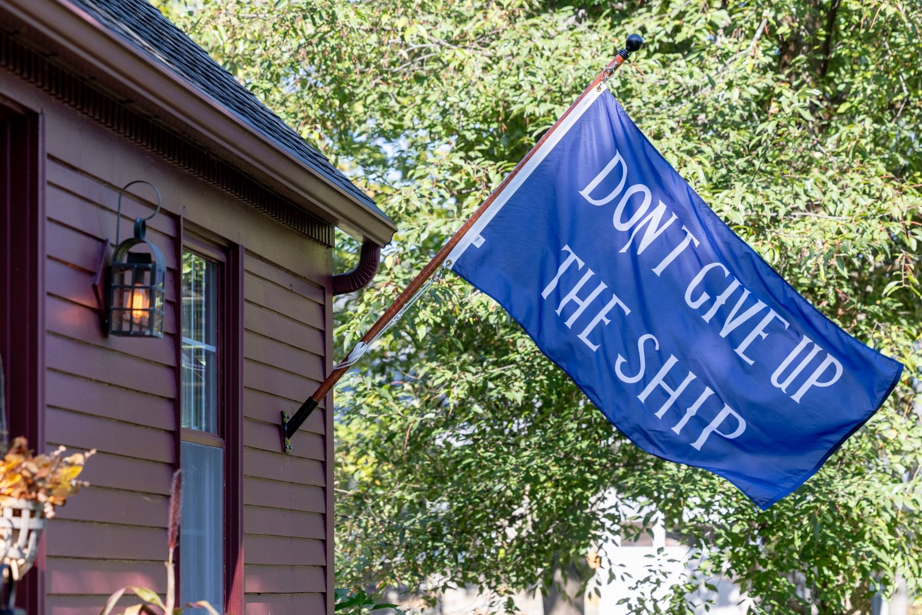 Commodore Perry Don't Give Up the Ship flag flying from a residential house-mount bracket and wooden pole