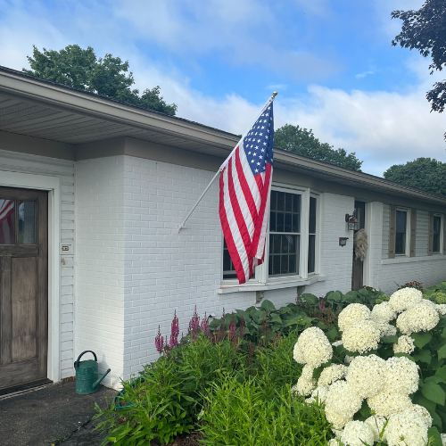 American flag on home with white brick